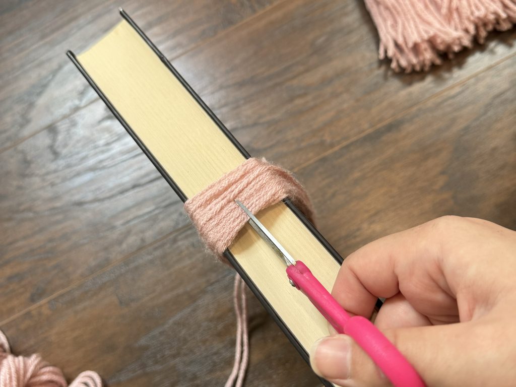 cutting yarn on opposite side of the book to create yarn tassel