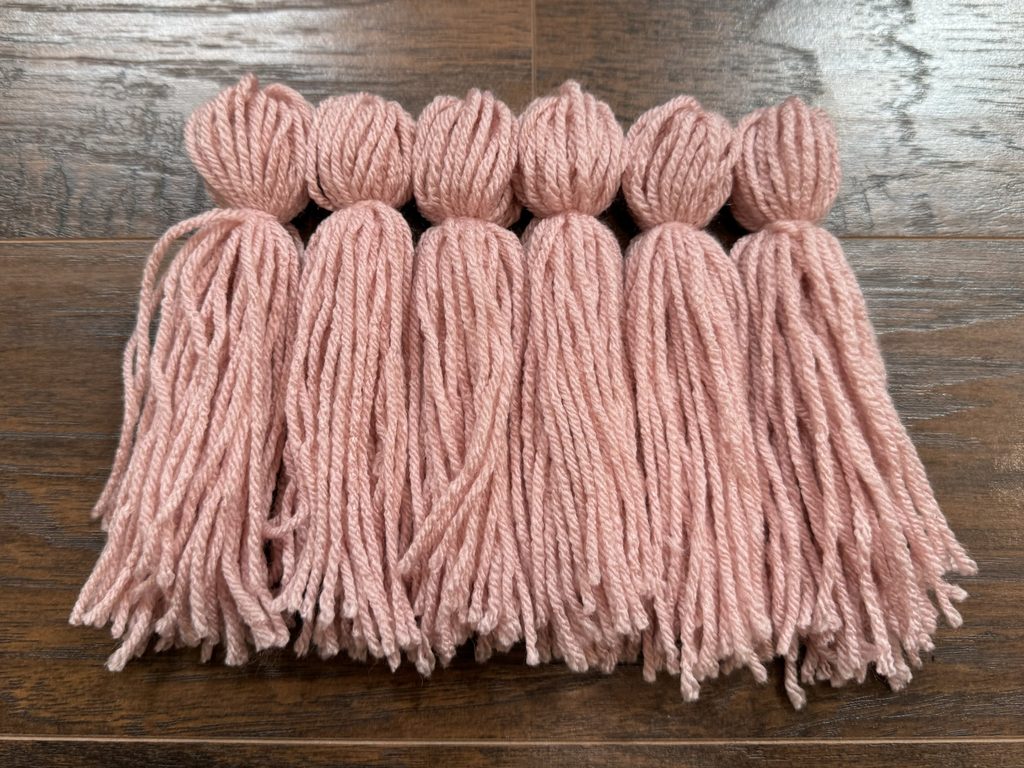 a set of six finished pink yarn tassels